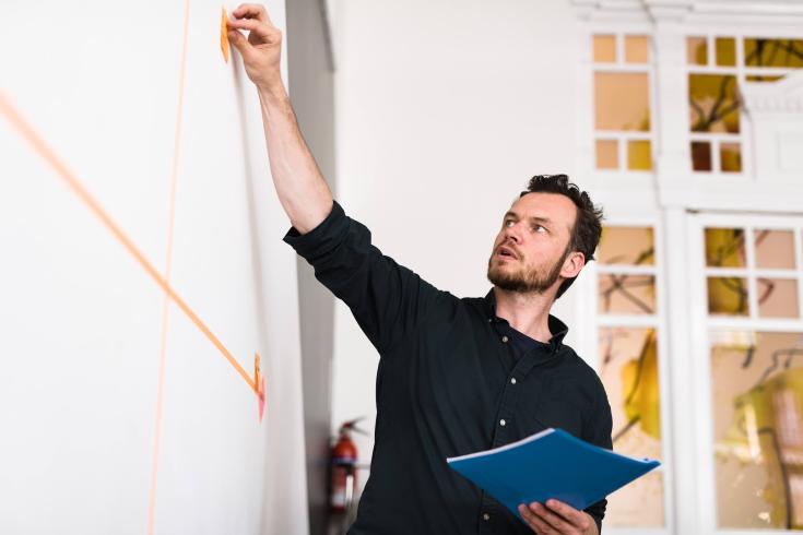 Man putting post it on board